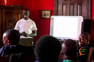 Sammy Ombisa with a group of men in a safe space discussing mental health and addiction Reciovery.